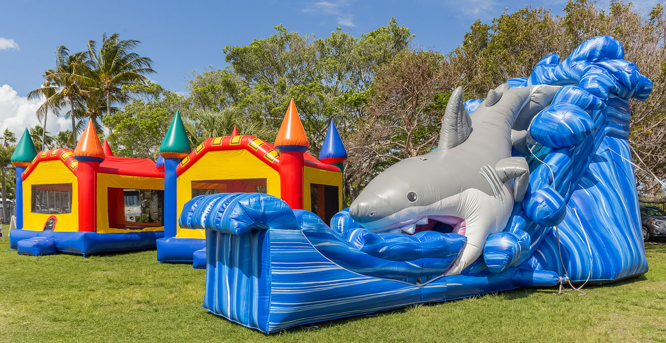 Deux structures gonflables installées côte à côte sur une pelouse, une petite et une grande avec toboggan