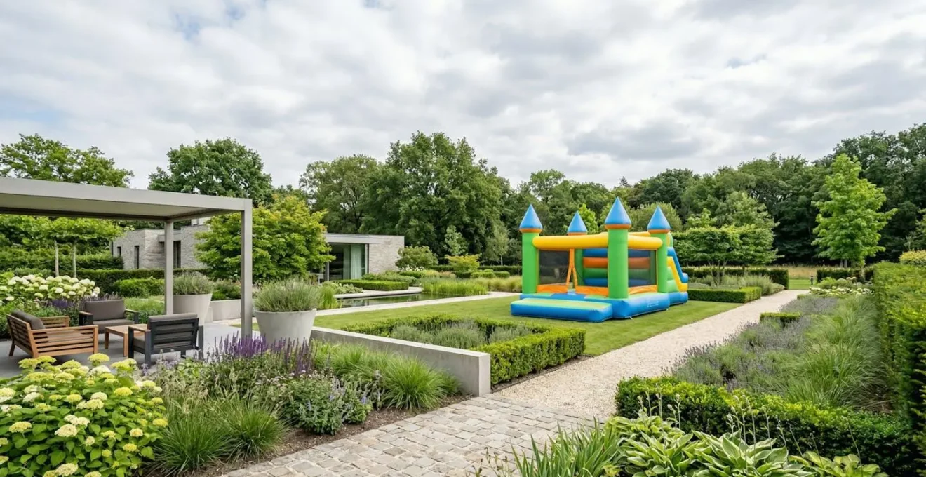 Vue large d'un jardin français moderne avec un château gonflable installé au second plan sous un ciel légèrement nuageux et lumineux